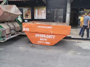 Caixa coletora laranja da Repe Entulho posicionada em rua de comércio
